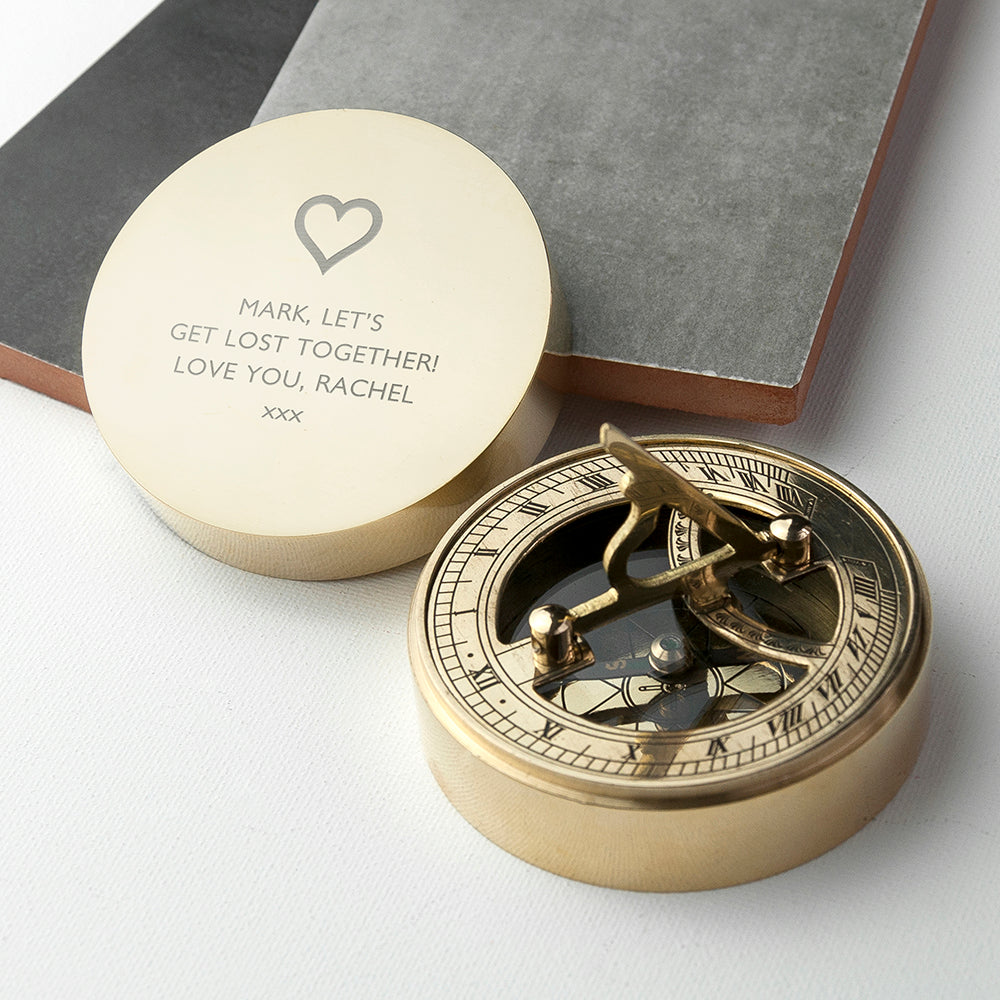 Brass compass with engraved message on a white surface