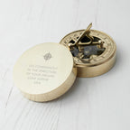 Brass compass with engraved message on a white wooden surface