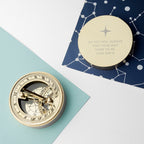 Gold compass on a geometric-patterned surface with a message card.