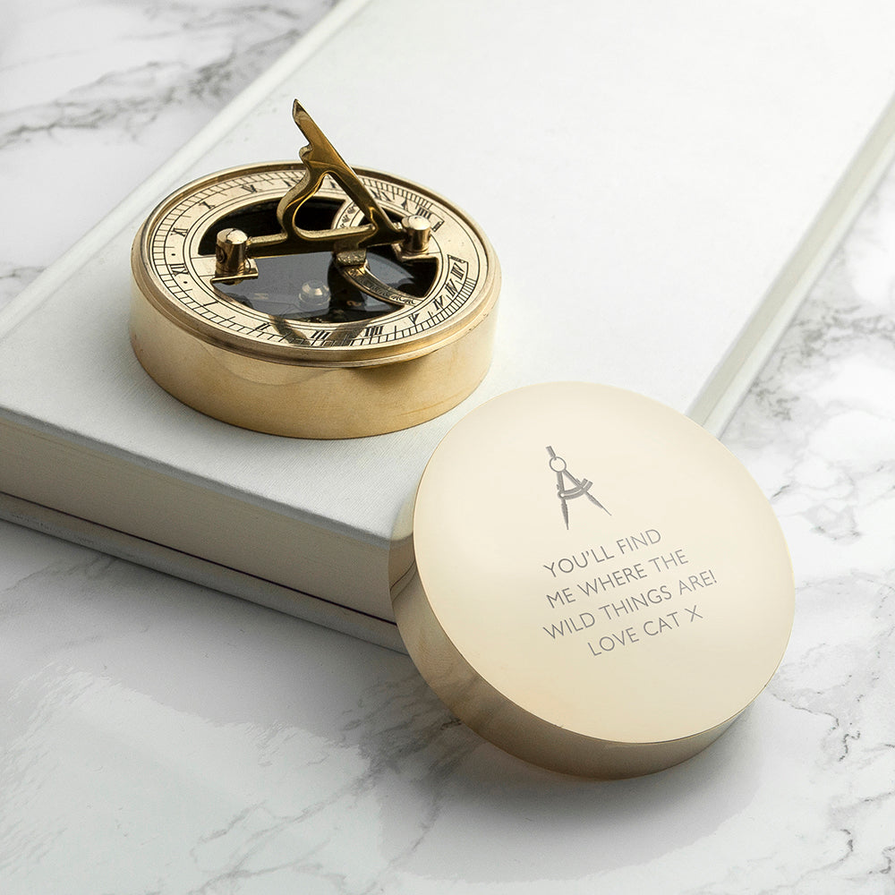 Gold compass with engraved message on a marble surface