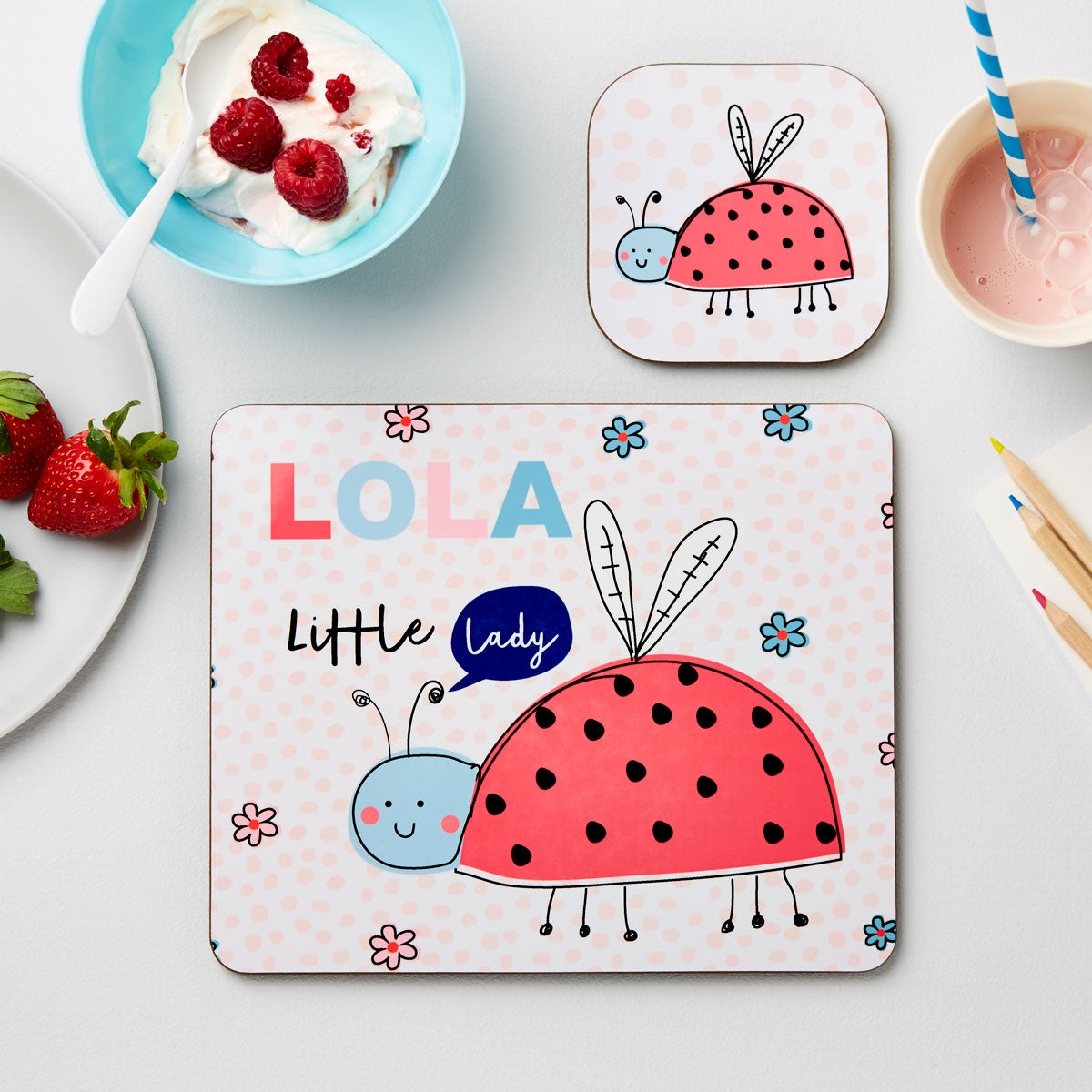 Two children's placemats with ladybug designs on a table with food.