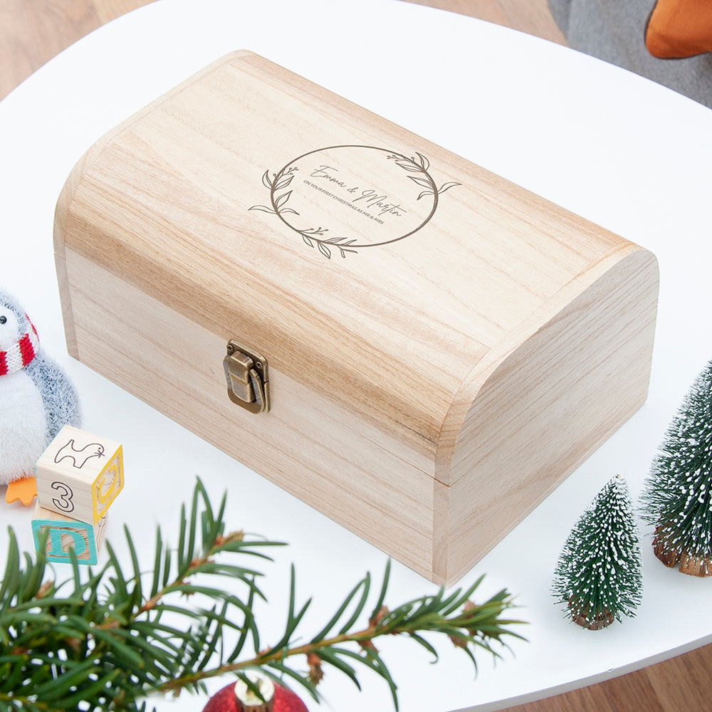Wooden box with engraved design on a white surface with Christmas decorations.