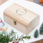 Wooden box with engraved design on a white surface with Christmas decorations.