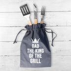 Gray drawstring bag with BBQ tools and 'Dad, The King of the Grill' text on a wooden surface