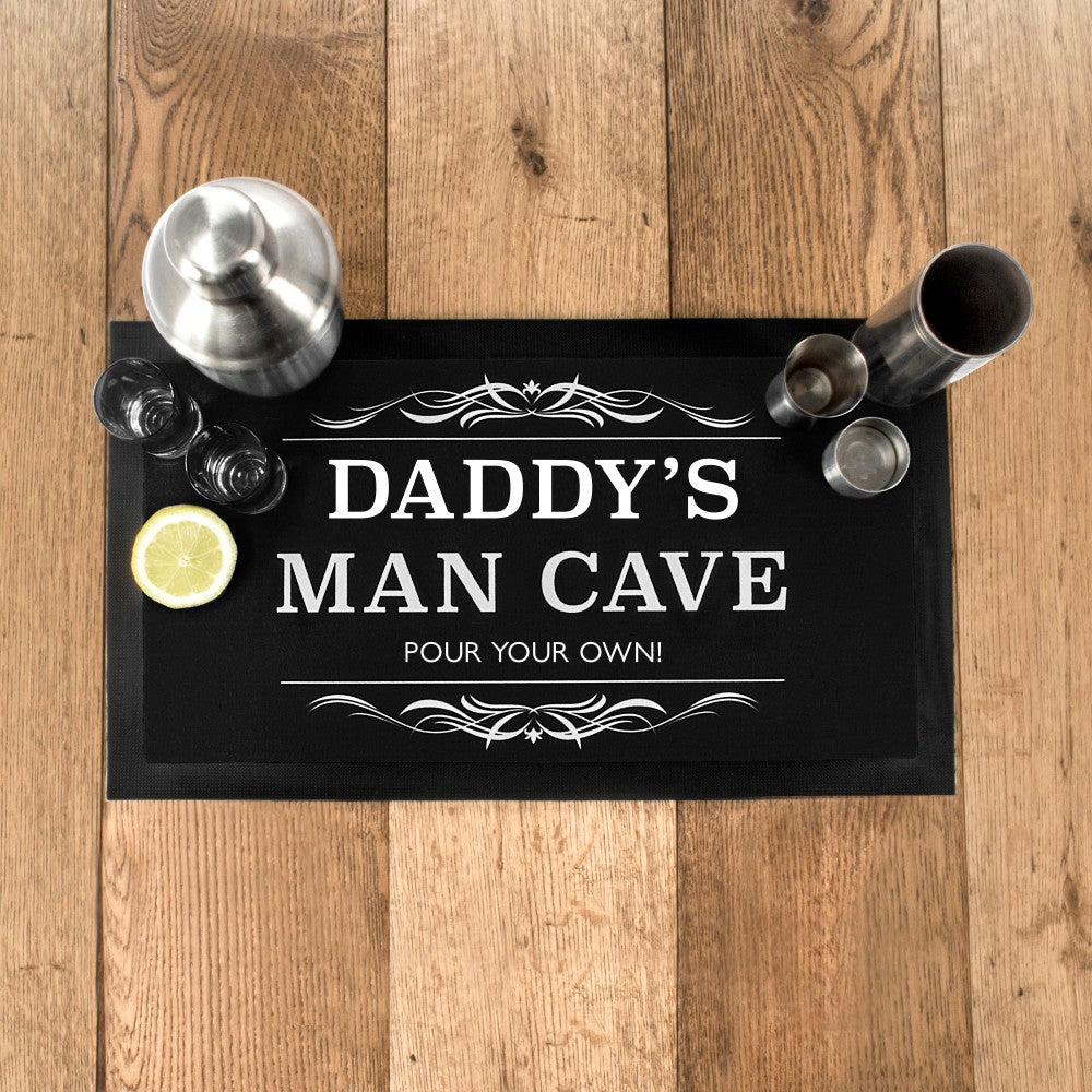 Bar sign with 'Daddy's Man Cave' text on a wooden surface with bar accessories.