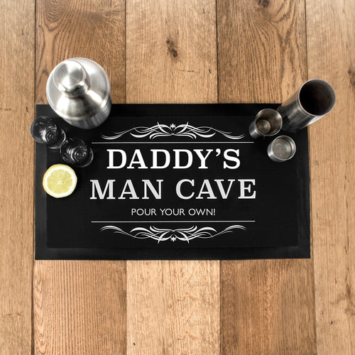 Bar sign with 'Daddy's Man Cave' text on a wooden surface with bar accessories.