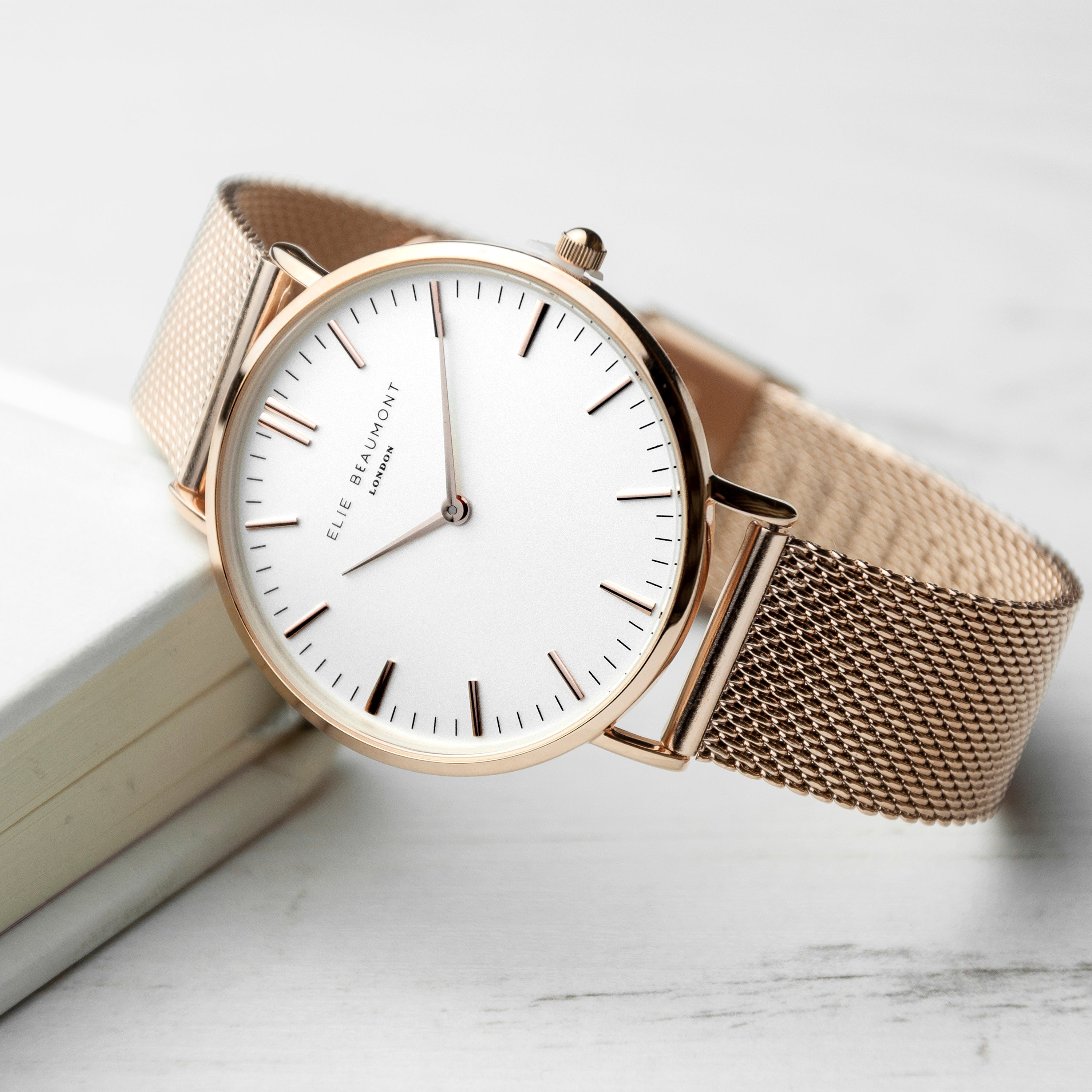 Wristwatch with beige mesh strap on a light background