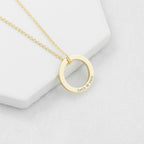 Gold necklace with a circular pendant on a light gray background