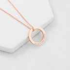 Rose gold necklace with 'world's best mom' pendant on a light gray background