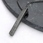 Necklace with a pendant engraved 'PAPA BEAR' on a dark surface.