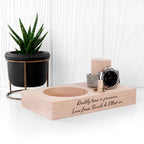 Wooden desk organizer with a watch, candle, and small plant on a white surface.