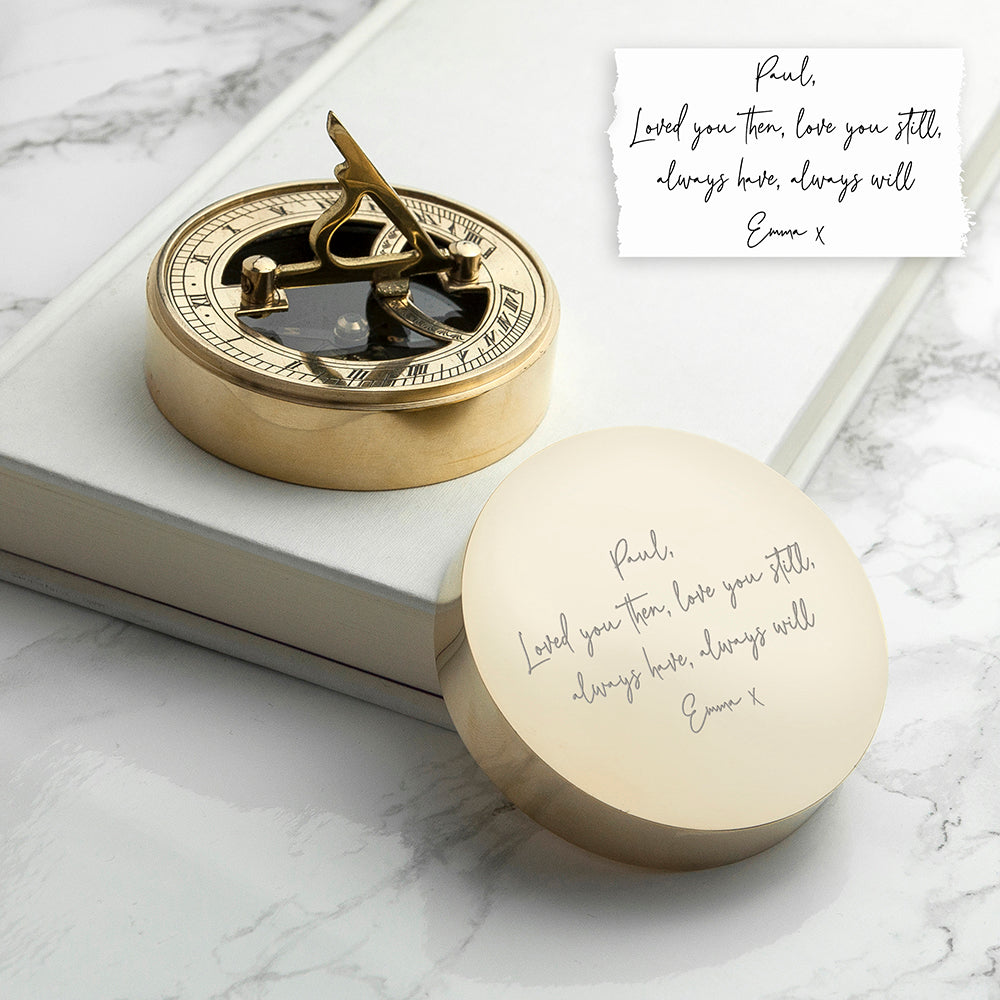 Gold compass and decorative box on a marble surface with a romantic message.