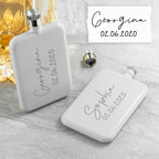 Two white flasks with personalized names and dates on a gray surface.