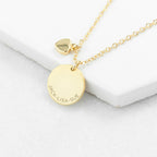 Gold necklace with a round pendant on a white surface