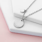 Silver necklace with engraved pendant on a white surface