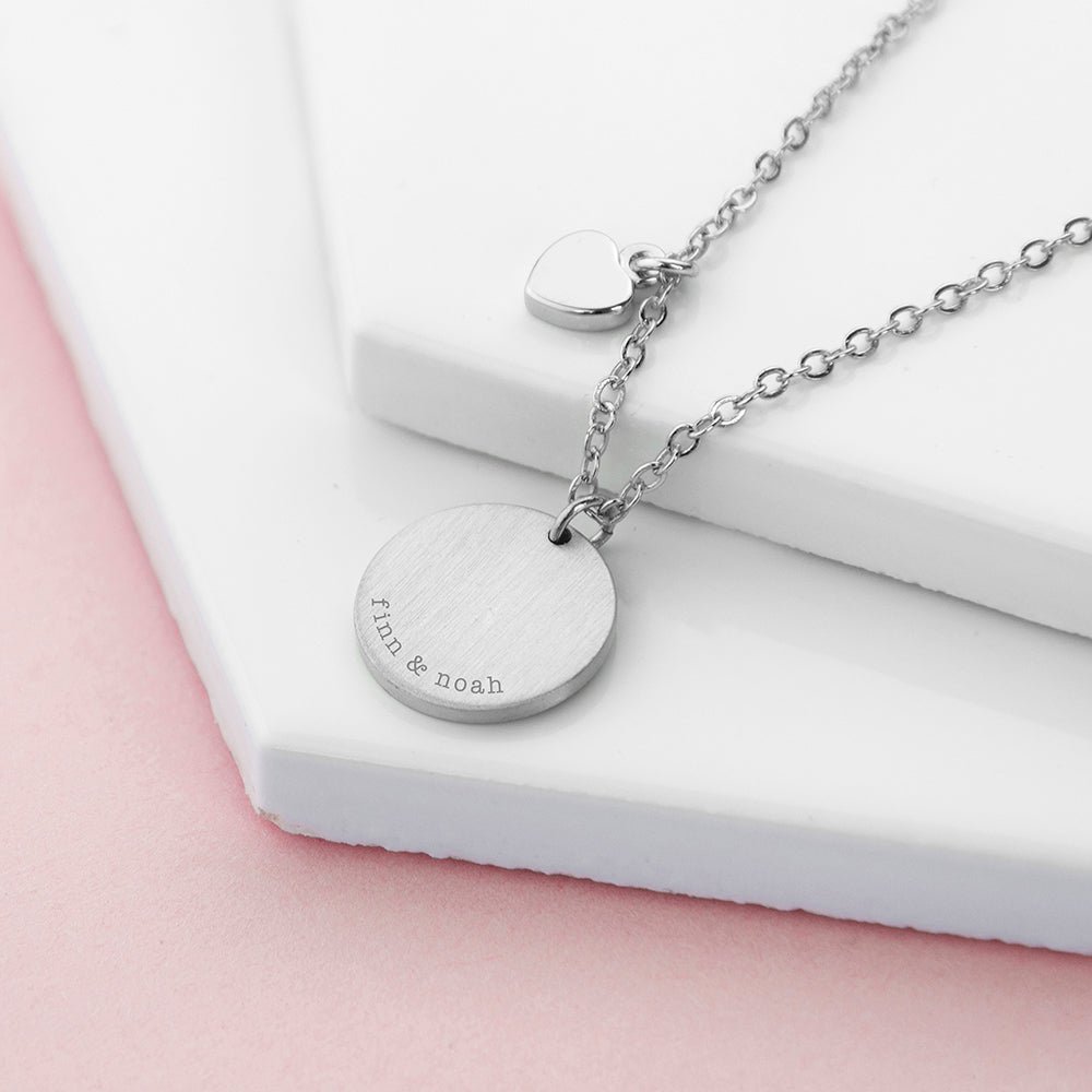 Silver necklace with engraved pendant on a white surface