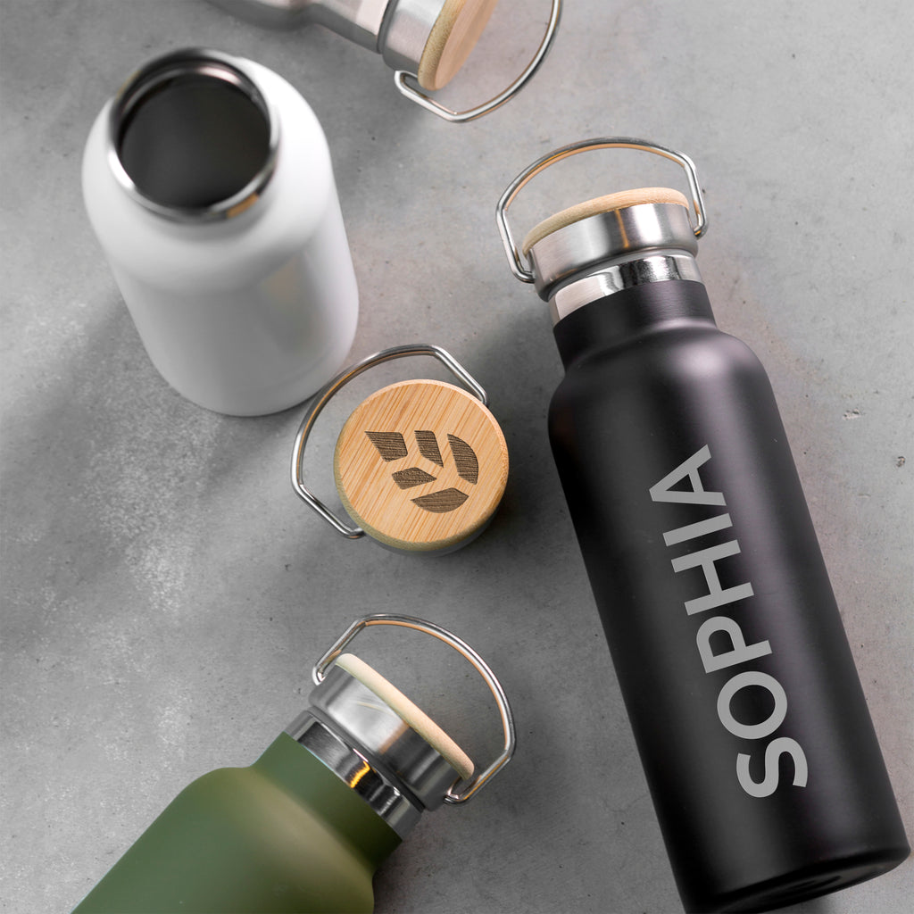 Three insulated bottles with wooden caps on a gray surface, one labeled 'SOPHIA'.