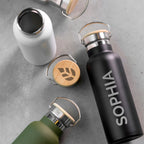 Three insulated bottles with wooden caps on a gray surface, one labeled 'SOPHIA'.