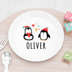 White plate with cartoon penguins and 'OLIVER' text on a wooden table.