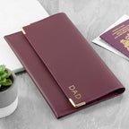 Maroon passport holder with 'DAD' engraving on a light gray surface.
