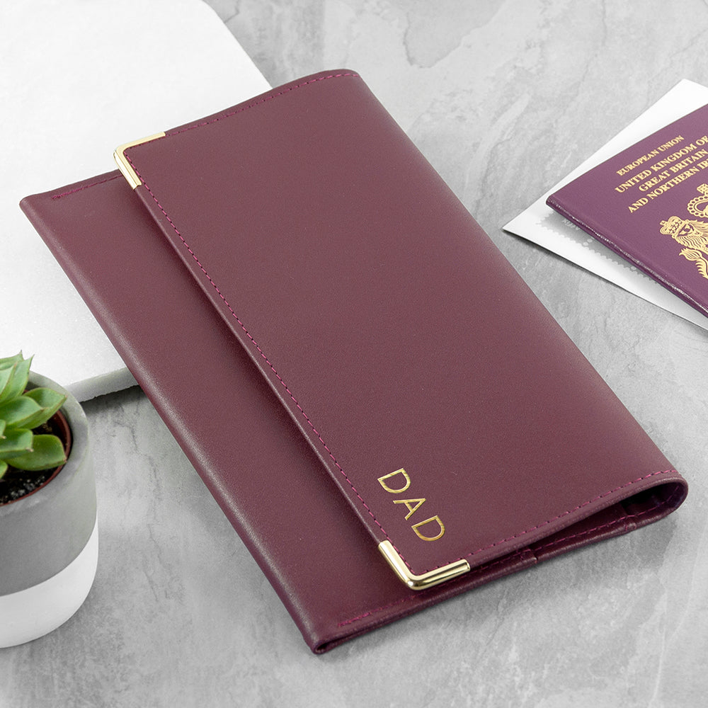 Maroon passport holder with 'DAD' engraving on a light gray surface.