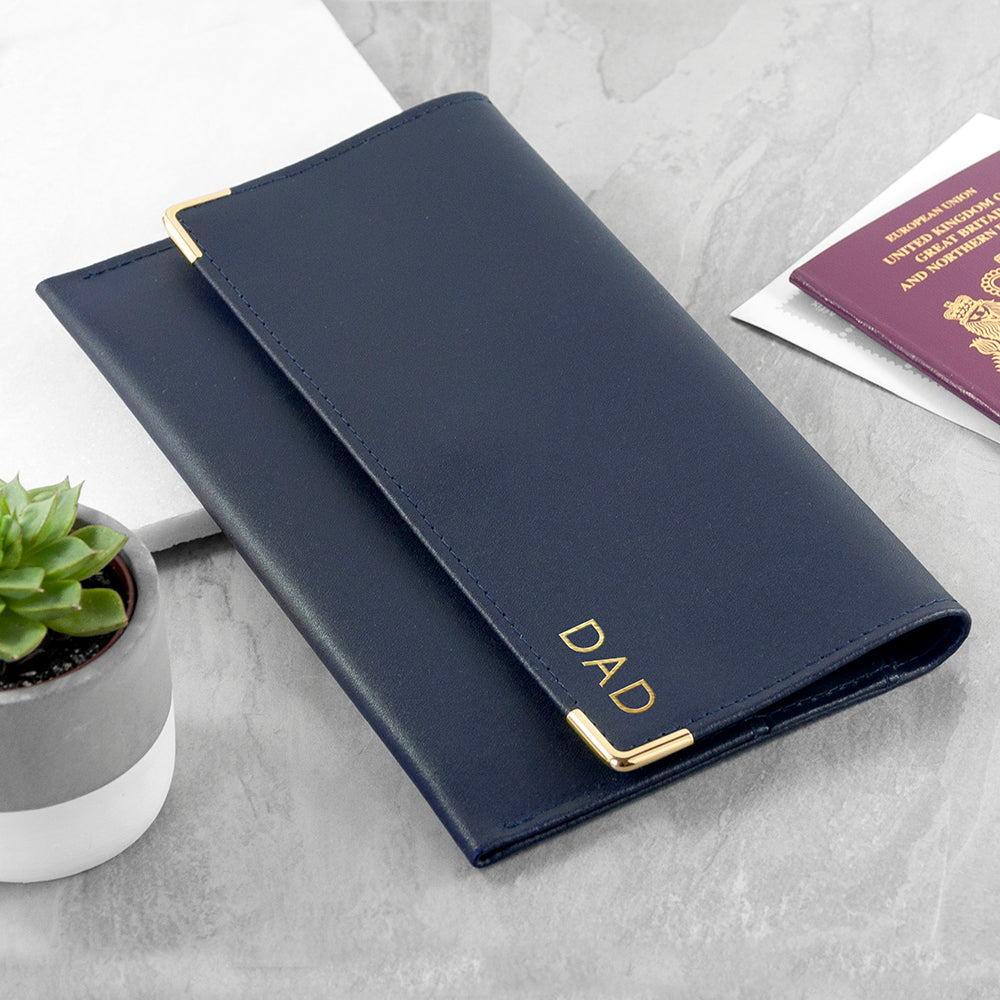 Navy blue passport holder with 'DAD' engraving on a light gray surface.