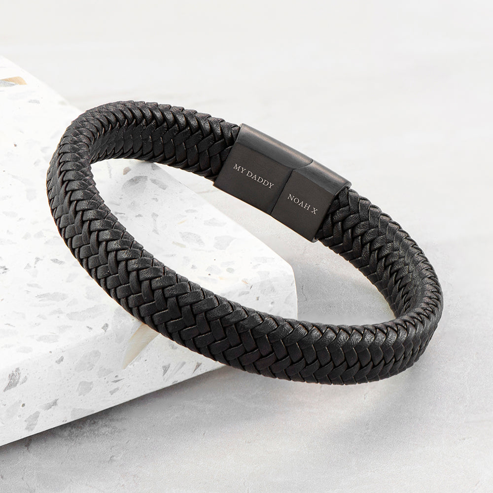 Black braided bracelet with a metallic clasp on a light gray background
