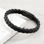 Black braided bracelet with a clasp on a light gray background