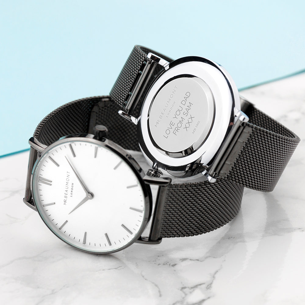 Two black mesh watches with white faces on a marble surface.