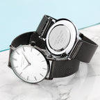 Two black mesh watches with white faces on a marble surface.