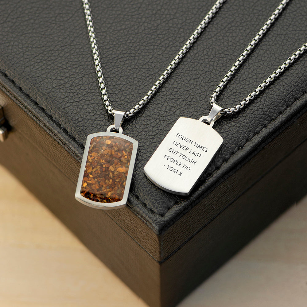 Two silver necklaces with engraved pendants on a dark surface