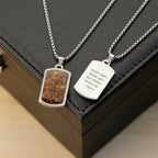 Two silver necklaces with engraved pendants on a dark surface
