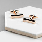 Rose gold cufflinks with 'KGR' engraving on a white surface