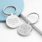 Two silver keychains with engraved messages on a light blue and white background