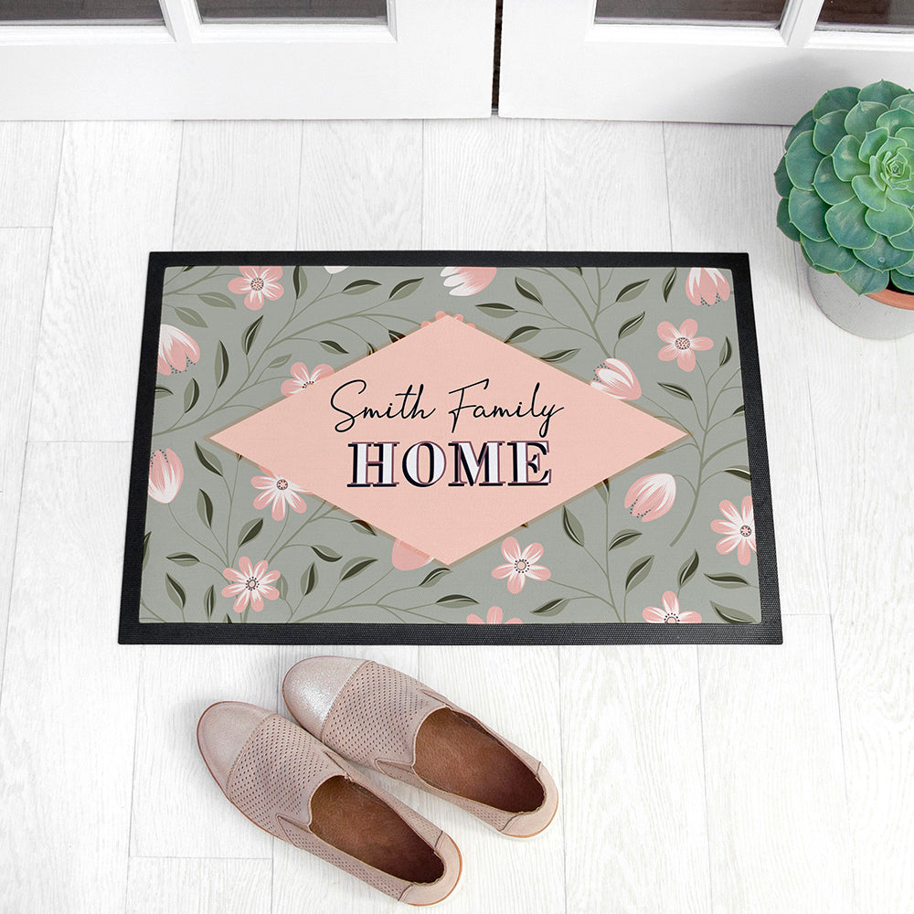 Decorative doormat with floral pattern and 'Smith Family HOME' text on a white floor with shoes and a plant.