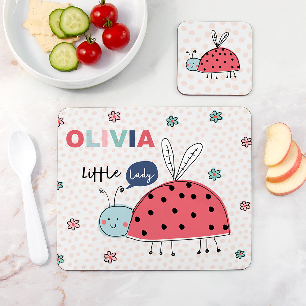 Children's placemat with a ladybug design and the name 'Olivia' on a table with snacks.