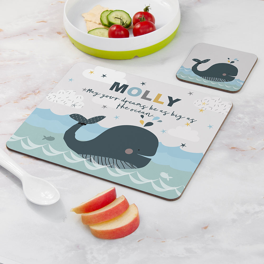 Personalized placemat with whale design and message, placed on a marble surface with fruit and a bowl.