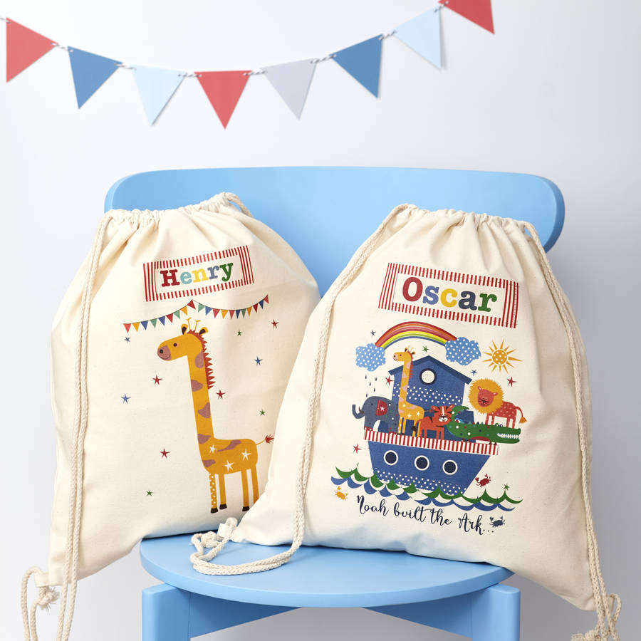 Two drawstring bags with cartoon designs and names on a blue chair with a colorful flag banner.
