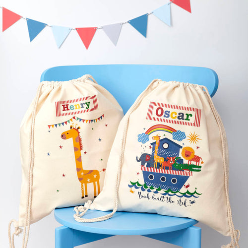 Two drawstring bags with cartoon designs and names on a blue chair with a colorful flag banner.