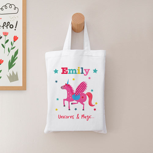 White tote bag with a unicorn design and the name 'Emily' on a beige wall.