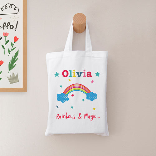 White tote bag with colorful design and text hanging on a wooden hook against a light wall.