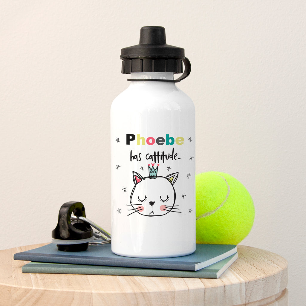 White water bottle with a cat illustration and text, placed on a wooden surface with a tennis ball and phone.