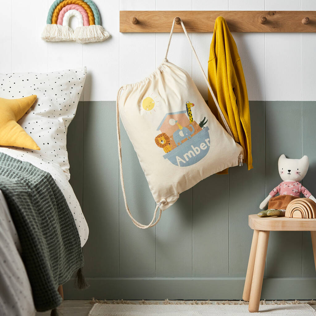Children's room with a drawstring bag, toys, and a rainbow decoration on a wall.